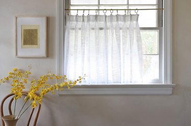No-sew white pinch pleat cafe curtain hanging in window next to picture and yellow flowers