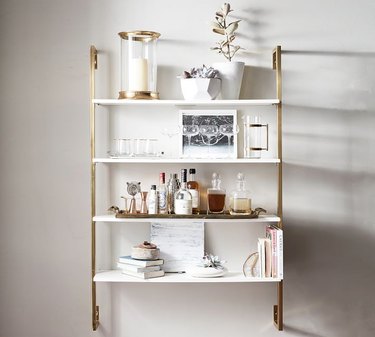 White shelving unit with gold hardware on a grey wall