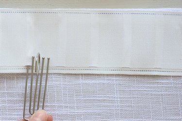 Inserting first prong of pinch pleat hook into pleater tape