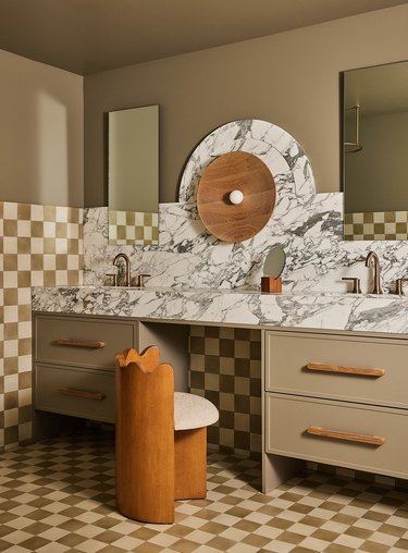 bathroom makeup vanity with marble countertop and backsplash and checkerboard tile