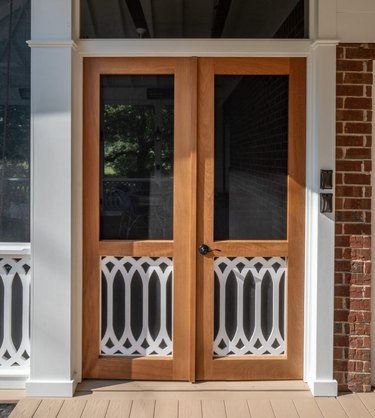 A pair of wooden screen doors with decorative bottom panels