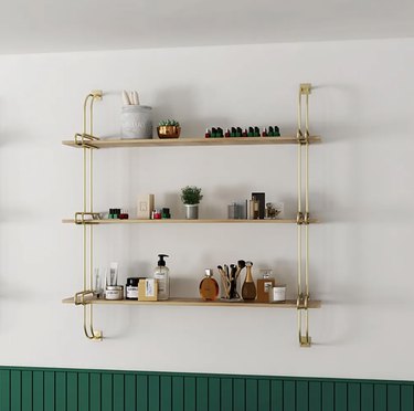 Floating wooden shelves with gold hardware on a white wall