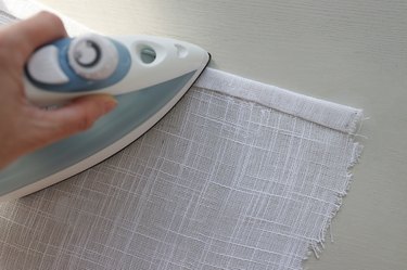 Ironing double hem on white linen fabric with no sew hemming tape
