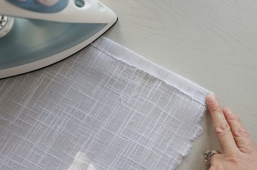 Ironing hem on white linen fabric