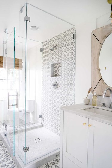 White and light-wood bathroom with mosaic tiled shower and flooring