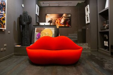 Red lip couch in taupe-painted living room with dark wood floors