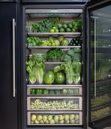 Refrigerator filled with green fruits and vegetables.