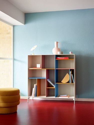 Room with red floor, light blue wall, and colorful bookshelf