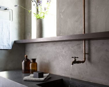 Minimalist organic bathroom with industrial copper-colored faucet and sleek sink ledge