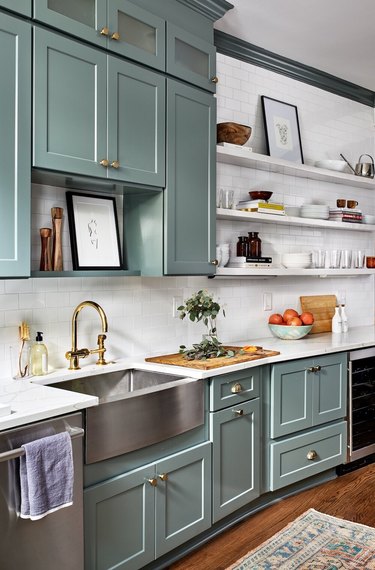 Kitchen with white walls, turquoise cabinets, and gold hardware