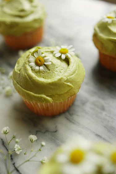 DIY sage green frosted cupcakes garnished with chamomile flowers