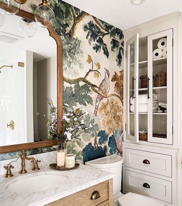 Bathroom with wallpaper, storage cupboard, drawers, vanity.