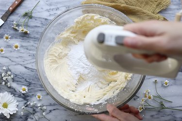 Mixing powdered sugar into butter with hand mixer