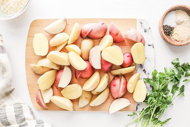 Sliced baby potatoes on a wooden cutting board