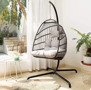 Hanging chair, end table, plant, rug.