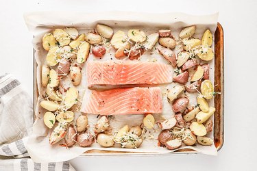 Salmon filets and sliced potatoes on a baking sheet