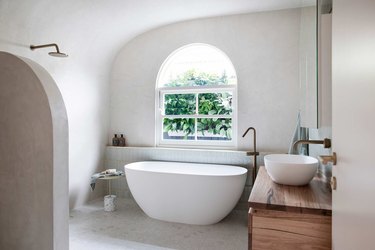 wet room with tub and shower featuring a plaster wall finish
