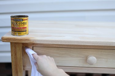 Applying wood stain to wood table with a white cloth