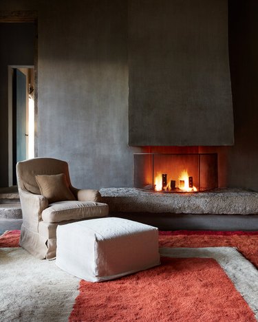 living room with charcoal gray plaster walls and fireplace and orange rugs