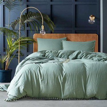 bedroom with navy blue walls and sage green bedding