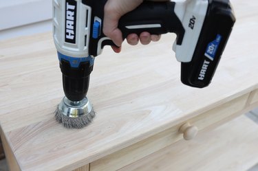 Scuffing up the top of a wood table with a wire brush attachment on a power drill