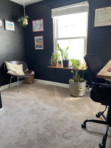 A home office with painted black walls and lots of plants.