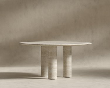 A travertine table with three chunky travertine legs.