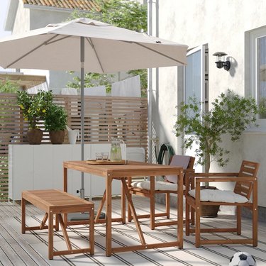 A wooden outdoor table with a white umbrella on a patio.