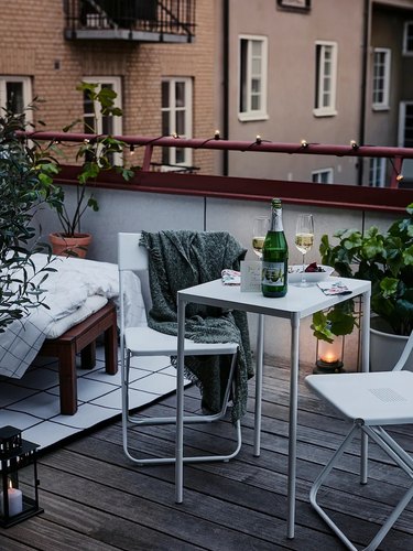 A white outdoor table with two matching chairs on a city balcony.
