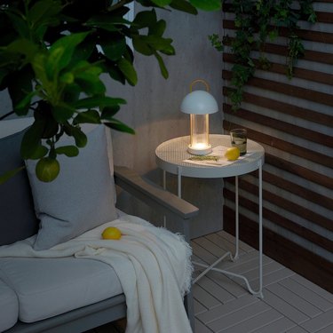 A mushroom-shaped LED light on a small white side table next to an outdoor couch and plants.