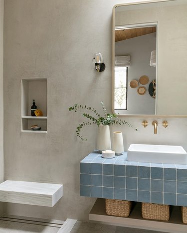 Modern minimalist bathroom with concrete walls and a blue tiled vanity