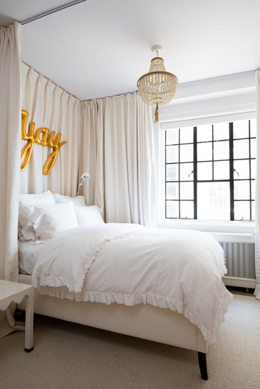 White bedroom with cream-colored drapes around bed