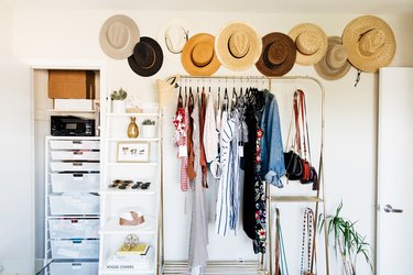 small bedroom storage idea: clothing rack and hats hanging from wall
