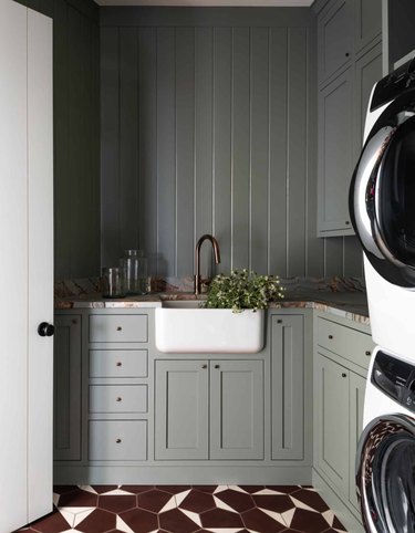 Kitchen with olive green cabinets, burgundy tile floor, apron sink.