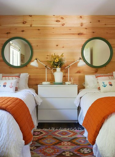 pine-clad bedroom walls with green mirrors and orange blankets