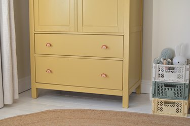 Yellow childrens cabinet with rainbow door knobs