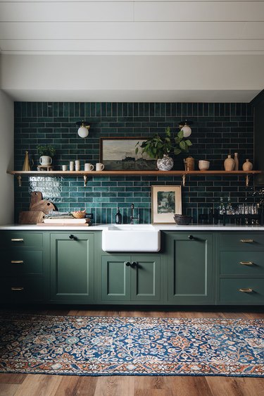 Kitchen with sage green cabinets and teal backsplash tile.