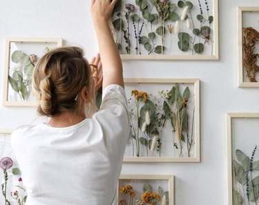 Woman hanging framed flowers