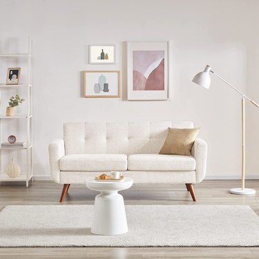 white loveseat with tufting in neutral room