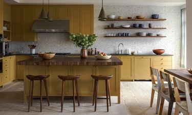 Mustard yellow kitchen cabinets and floating wood shelves