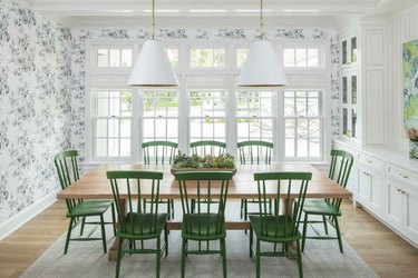 Green, white, and light-wood dining room with green Windsor chairs and white pendant lights.