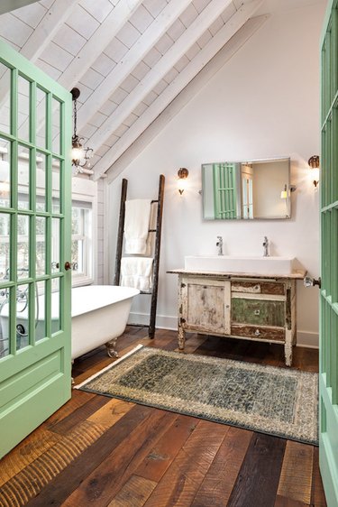 Green French doors leading into a master bathroom with a clawfoot tub