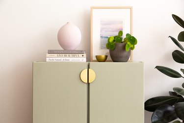 IKEA Ivar cabinet painted green with gold handles and styled vases on top