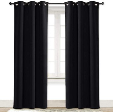 Black soundproof curtains hung up over a window