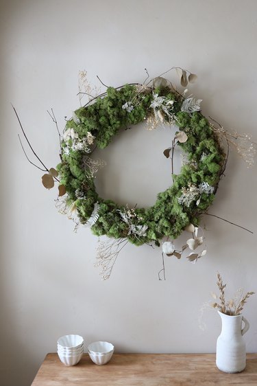 DIY moss and dried floral wreath hanging on wall