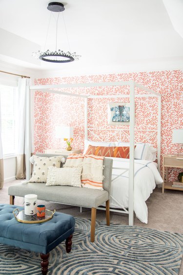 Bedroom with white bedding, orange wallpaper, and orange accessories