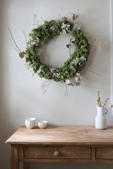 DIY moss and dried floral wreath hanging on wall