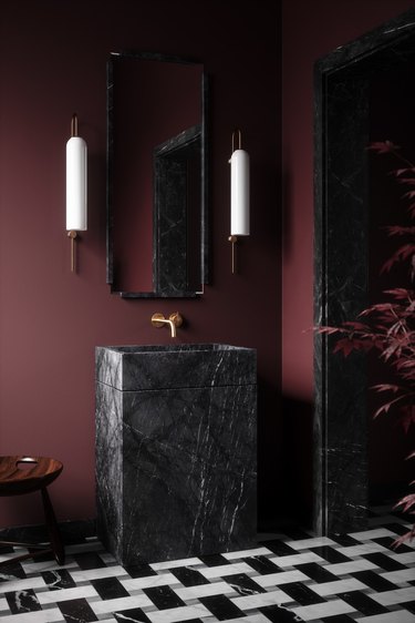 bathroom with maroon walls, black stone sink, and black and white tile floor