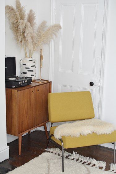 mustard yellow chair with cream details and midcentury cabinet