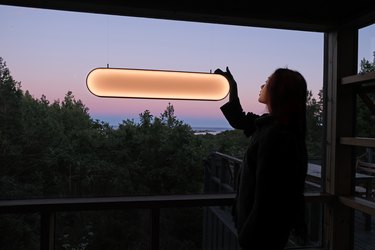 person turning on solar light on window with trees in the background